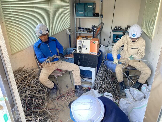 電線を銅線と被覆に分別する作業を行うスタッフと技能実習生